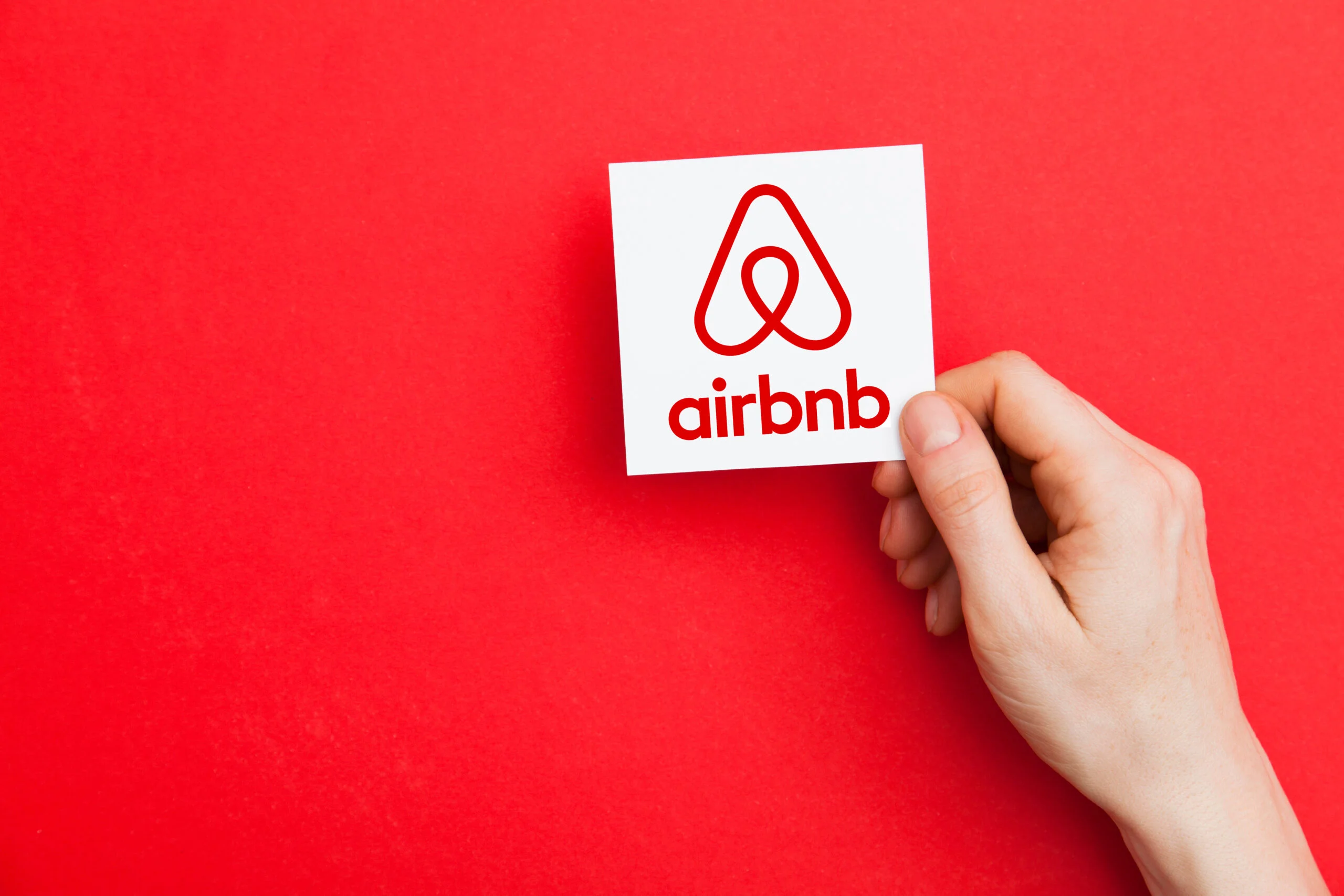 A persons hand holding a card and says 'airbnb' with the logo above.