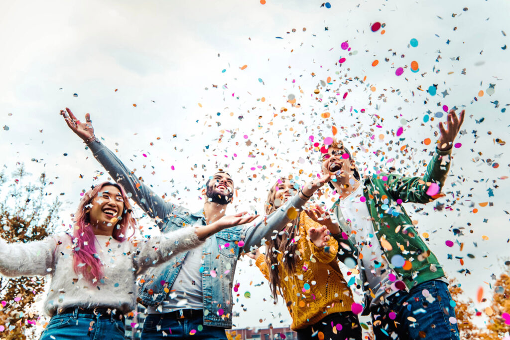 Happy friends celebrating throwing confetti in the air