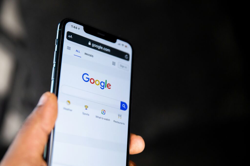Someone holding phone up with Google search engine showing
